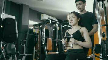 kvinna bär träna kläder där är manlig utbildare till övning med övning maskiner. video