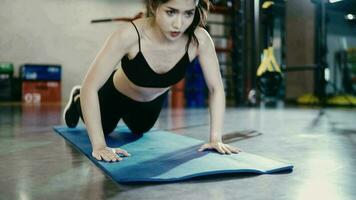 Frau tragen trainieren Kleider auf ein Yoga Matte tun Liegestütze beim das Fitnessstudio. video