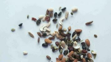 Top view of many mixed nuts falling on white background video
