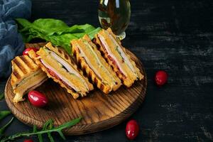 Club sandwich with ham, cheese, tomato and salad. Grilled sandwich with dried tomatoes bread photo