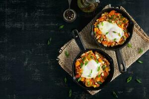 Shakshouka in frying pan. Fried eggs with vegetables, tomato, pepper, pumpkin and onion. Top view photo