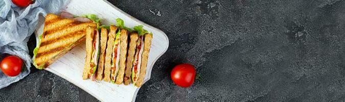 Club sandwich with ham, tomato, green and cheese. Grilled panini. Top view photo
