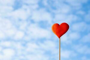 Red heart against blue cloudy sky photo