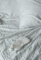 Sleep eye mask lying on white bedding. Awaking or insomnia concept. photo