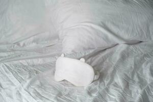 Sleep eye mask lying on white bedding. Awaking or insomnia concept. photo