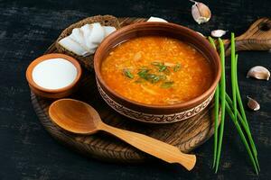 Cabbage soup in bowl with green onion, bread and salo on dark background photo