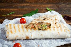 Delicious chicken shawarma sandwich with salad and cheese on wooden background photo