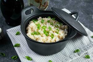 Stewed rice with chicken in a pot on dark grey background photo