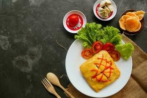 nasi goreng pattaya or Pattaya Fried Rice, Stuffed Omelette Fried Rice. Southeast Asian dish made by covering or wrapping chicken fried rice, in thin fried egg or omelette photo