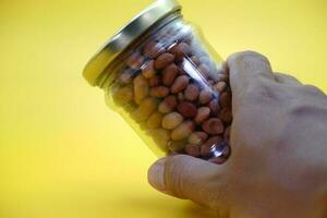 glass jar full of shelled peanuts. hand holding a glass jar filled with nuts photo