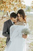 Happy wedding couple in countryside. Amazing smiling wedding couple. Pretty bride and stylish groom. He kisses her shoulder. She is happy and enchanted. photo