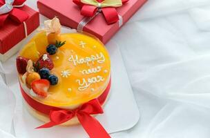 Orange cake with happy new year and topped with orange, strawberry, blueberry and Cape Gooseberry photo