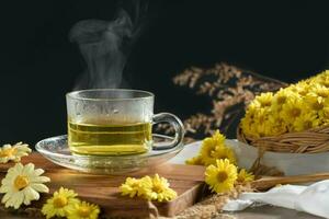 crisantemo té con caliente vapor y crisantemo flor en cesta en negro antecedentes. foto
