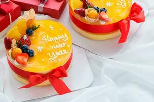 Orange cake with happy new year and topped with orange, strawberry, blueberry and Cape Gooseberry photo