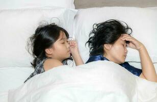 Sick Mother feels headache lying on bed near daughter, photo