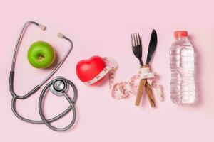 verde manzana con estetoscopio y medición cinta alrededor tenedor y cuchillo aislado foto