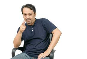 A middle-aged man with a beard in a blue T-shirt and jeans pointing at the camera isolated photo