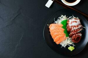 salmón y tako sashimi en negro plato con palillos, foto