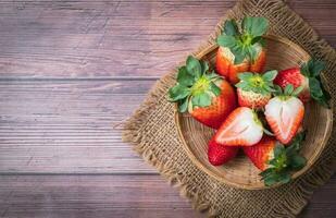 Fresh sliced strawberry in bamboo basket on wood table, photo