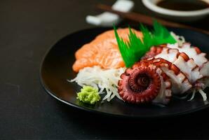 Tako and Salmon sashimi on black dish with chopsticks, photo