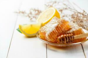panal en plato con miel cazo con limones en blanco madera fondo, foto