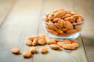 Almendras nueces pelado en vaso cuenco en madera mesa foto