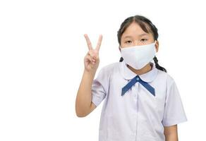 Asian student girl wear mask against infectious Virus and show victory sign hands isolated on white. photo