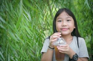 Happy cute girl drinking honey and lemon tea with ice photo