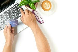 hand man typing on laptop and using credit card for online shopping on white table photo