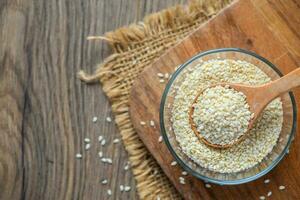 White sesame seeds in a wooden spoon on wood table. photo