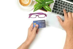 hand man typing on laptop and using credit card for online shopping on white table photo