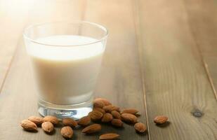 vaso de Leche y Almendras nueces en madera fondo, foto