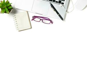White office desk table with laptop computer and blank notebook isolated on white photo
