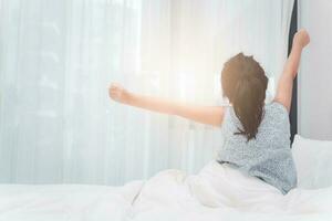 espalda lado de pequeño niña extensión en cama después despertar arriba foto