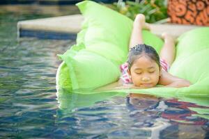 linda pequeño niña jugar aire colchón en nadando piscina, foto