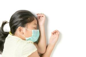 Sick little girl wearing a protective mask lying on white photo