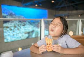 linda asiático niña disfrutar a comer un pan a conveniencia Tienda foto