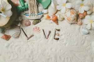 love text with Shells and plumeria flowers on sand background, photo