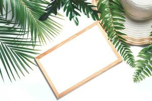 Blank white wood frame with tropical leaf and big hat isolated photo