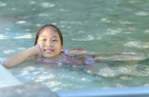 sonriente linda pequeño niña en nadando piscina foto