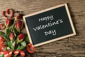 Valentine's day text on blackboard with red roses photo