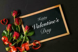 Valentine's day text on blackboard with red roses photo