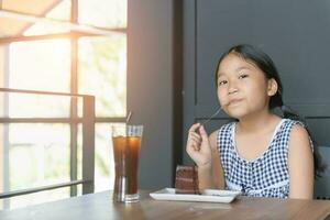 kid enjoy eating chocolate and and ice tea in coffee shop, photo