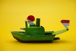 boat otok otok, a traditional toy from Indonesia. a pop pop boat toy that uses steam power. toy ship isolated yellow background. photo