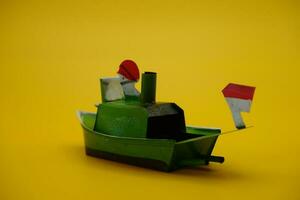 boat otok otok, a traditional toy from Indonesia. a pop pop boat toy that uses steam power. toy ship isolated yellow background. photo