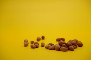 pile of peeled peanuts isolated on yellow background photo