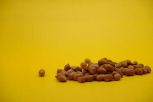 pile of peeled peanuts isolated on yellow background photo