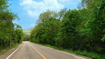 la carretera va Derecho adelante de el asfalto la carretera y el curva a el final en tailandia dos sitiar con verde bosque y debajo azul cielo y blanco nubes foto