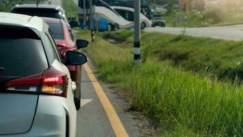 Back of a gray car with a turn signal for a U-turn. Long line of cars and blurred view of U-turn bus. Beside asphalt road with green grass. photo