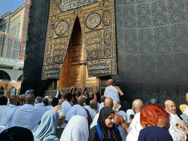 Mecca, Saudi Arabia, April 2023 - Umrah pilgrims from all over the world gather in the courtyard of Masjid al-Haram near the door of the Kaaba. photo